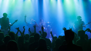 blue lights on a stage with a band singing and a crowd with their hands up